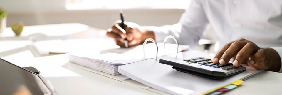 Personne en chemise blanche travaillant sur documents comptables dans bureau moderne
